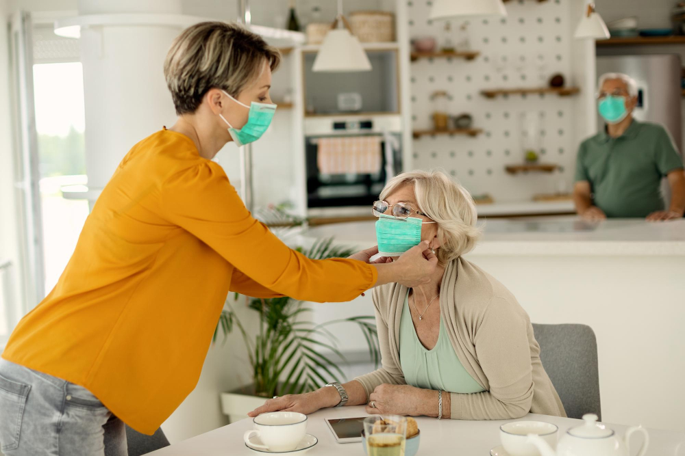Female caregiver assisting elderly woman with face mask – safe and compassionate home care support