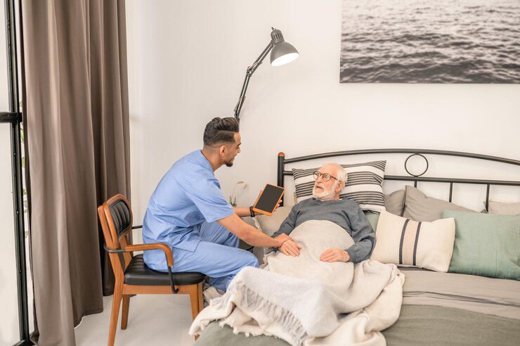 Healthcare professional providing compassionate support to a bedridden elderly man in a home setting, reflecting Lasting Legacy Healthcare Services' commitment to dignified in-home care.