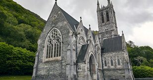 Historic stone building with gothic architecture surrounded by greenery, representing community heritage and support for seniors in Pasco County.