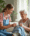 Non-medical home health aide assisting elderly woman with daily tasks in a cozy living room.